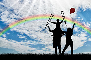 a family playing outside with a rainbow in the sky
