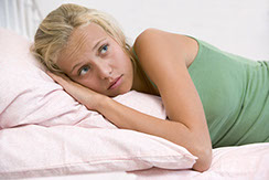 a young woman laying on a light pink pillow